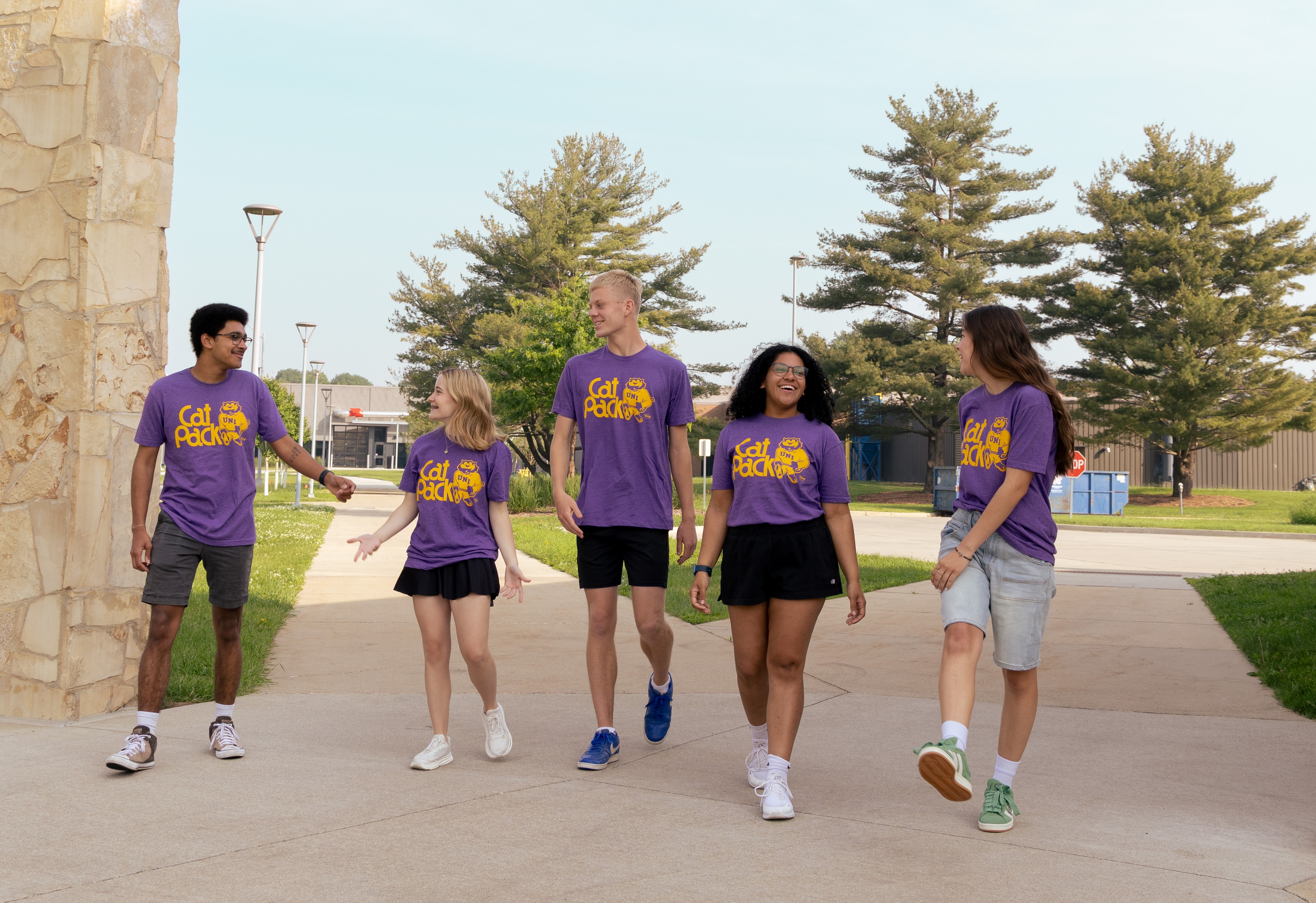 Five students wearing TC's Tee shirt which says "Cat Pack" and has a vintage logo of TC.