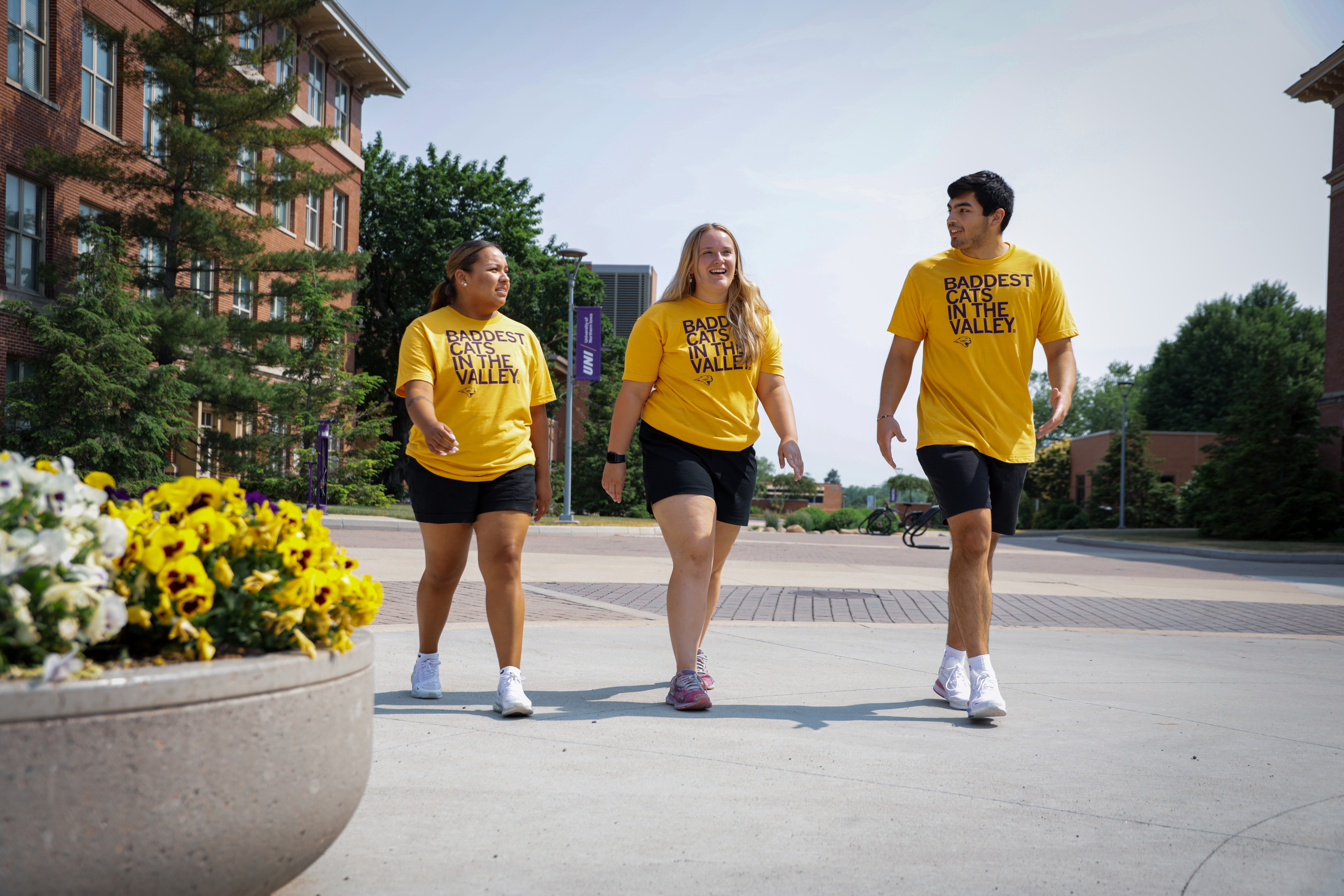 Students walking on campus wearing TC's Tee