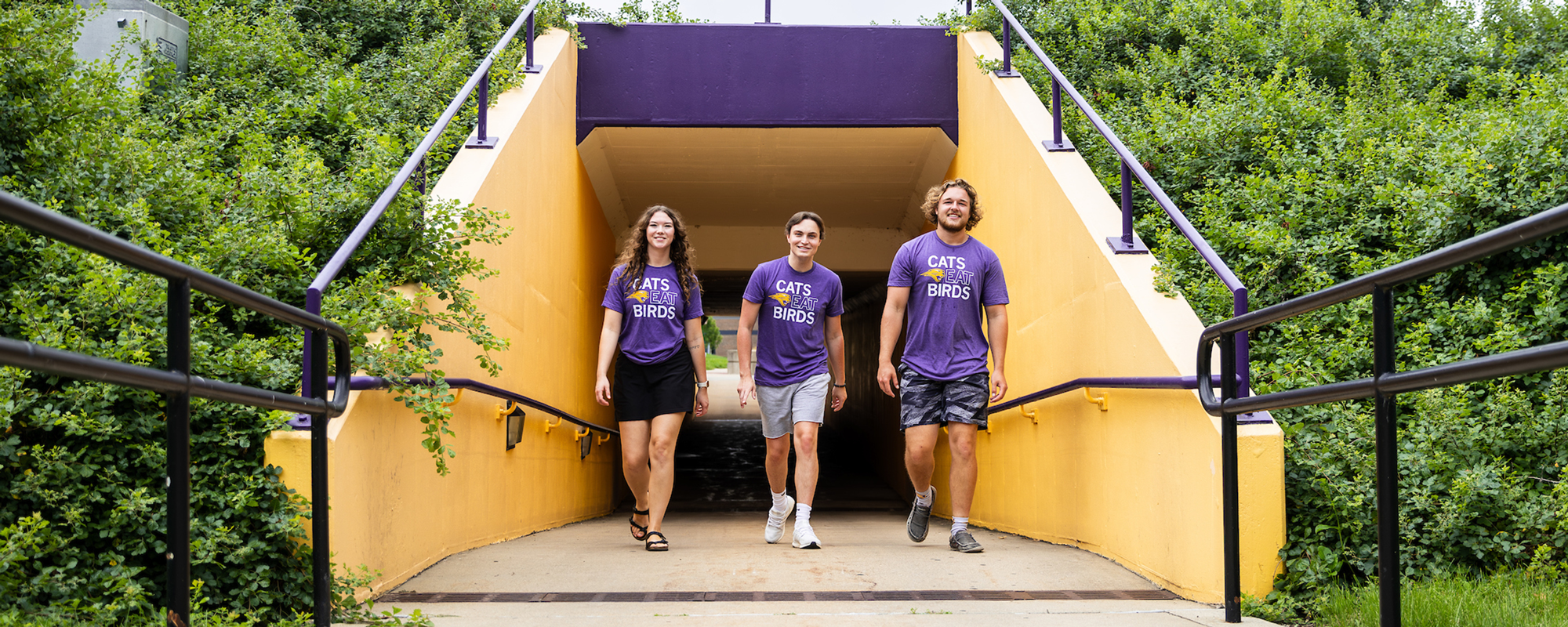 Students walking on campus wearing TC's Tee