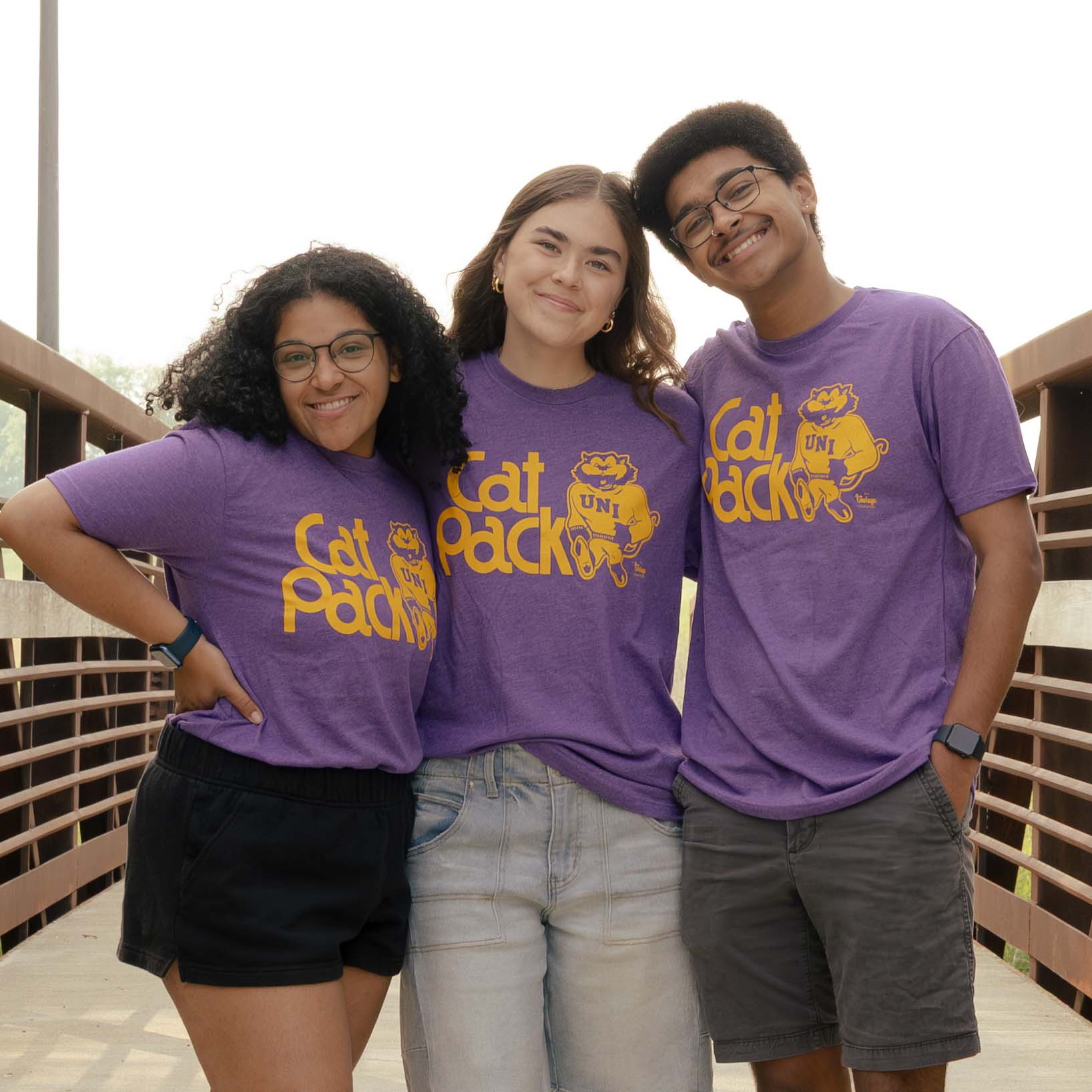 Three students wearing TC's Tee shirts that read "Cat Pack"